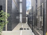 ACPレジデンス中野新橋 建物と外壁に囲まれた落ち着いた印象の共用通路