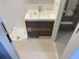 ACPレジデンス中野新橋 白を基調とした洗面室に濃木目の収納付き洗面台を配置