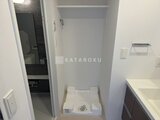 ACPレジデンス中野新橋 洗濯機置き場と上部収納を備えた明るいランドリースペース
