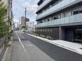 ジェノヴィア北千住 前面道路から見たモダンな建物外観と周辺街並み