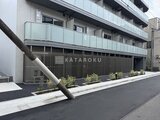 ジェノヴィア北千住 前面道路から見たモダンな建物外観と駐車場入口