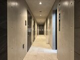 ジェノヴィア北千住 明るい照明が入る共用廊下と複数のドアが並ぶ様子