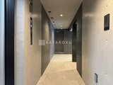 ジェノヴィア北千住 落ち着いた色調でまとめられた廊下からエレベーターへ向かう様子