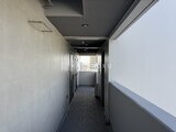 ジェノヴィア北千住 複数の玄関扉が並ぶ廊下と採光窓から見える街並み