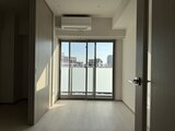ジェノヴィア北千住 明るい日差しが差し込むモダンなワンルーム、都市風景を望む大き