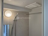 ジェノヴィア北千住 シャワーヘッドと丸形照明が備わった落ち着きのあるバスルーム