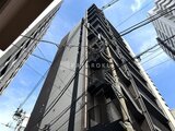 コンシェリア町屋 下から見上げた縦長のマンション外観と青空
