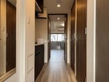コンシェリア町屋 木目調ドアと白い壁でまとめられた廊下からリビングダイニングへ