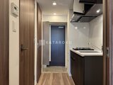コンシェリア町屋 黒を基調としたコンパクトなキッチンと玄関からの眺め