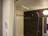 コンシェリア町屋 濃い木調パネルと白いタイルが調和するモダンな浴室