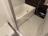 コンシェリア町屋 白い浴槽と石目調パネル、広めのバスルーム