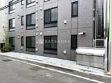 Aglaia 千石 Deux グレーのタイル張り建物と駐車スペースの外観