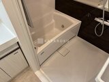Aglaia 千石 Deux 広々とした浴室に設置された白い浴槽と黒いアクセントパネル