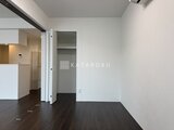 Aglaia 千石 Deux ダークフローリングと白壁が落ち着いた印象の洋室、奥にはウォー