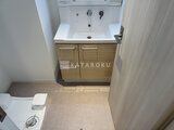 グランカーサ住吉2 木目調の洗面台とトイレが配置された、落ち着いた印象の洗面スペ