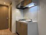 グランカーサ住吉3 木目調の扉と白い壁面がモダンな、コンパクトなキッチンの様子