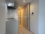 グランカーサ住吉3 コンパクトにまとめたキッチンと廊下、収納扉が並ぶ明るい空間