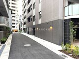アスマチメゾン両国2 落ち着いた色合いのアプローチ通路と植栽が配された建物外観