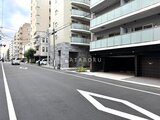 アスマチメゾン両国2 前面道路から見たモダンな建物エントランスと駐車場入口