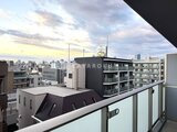 アスマチメゾン両国2 バルコニーから眺める都市風景と夕焼け空の様子
