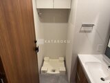 アスマチメゾン両国2 トイレ室内の洗浄便座と上部の収納棚がある様子