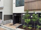 THE PALMS大島 黒板張りの外壁に木製デッキを備えたモダンなエントランス周辺の