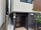 THE PALMS大島 黒いタイル張りのモダンなエントランスと植栽のある外観