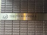THE PALMS大島 石貼りの建物壁面に輝くロゴサインが入ったエントランスの様子