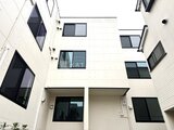 THE PALMS大島 白い外壁とグレーの窓枠で統一されたモダンな建物の中庭側の様子