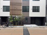 THE PALMS大島 前面道路から見たモダンな建物外観と緑のアプローチ