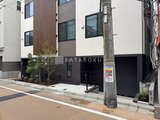 THE PALMS大島 前面道路から見たモダンな建物外観と黒色シャッター付きエントラ
