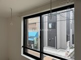 THE PALMS大島 大きな窓から駐車スペースと隣接建物が見える明るい室内