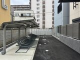 クレヴィアリグゼ蒲田西 屋根付き駐輪場と舗装駐車スペースが整備された共用部