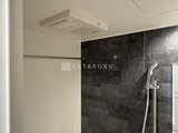 クレヴィアリグゼ蒲田西 黒いタイル壁とシャワーヘッド付きの浴室