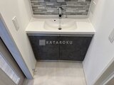 クレヴィアリグゼ蒲田西 白を基調とした洗面台と濃色の収納が調和する洗面室