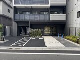 アークマーク大塚 前面道路から見たモダンな建物エントランスと駐車スペース
