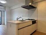 CREATIF蔵前 明るい印象のアイランドキッチン、天井埋め込み照明と黒いレンジ