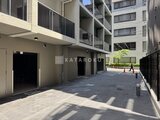 リビオメゾン浅草橋 開放的な共用庭から見た建物1階のエントランスと駐車場
