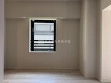 リビオメゾン浅草橋 黒いシェードが付いた窓から採光する落ち着きのあるリビング空間