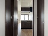 CREATIF本所吾妻橋 玄関から見たダークウッド調のキッチンと明るい居室空間