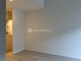 コンフォリア・リヴ押上ノース 明るい照明のキッチンコーナーが見えるリビングスペース