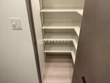 エスレジデンス王子イネーブル 奥行きのある棚収納スペースと木調床の廊下