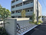 エスレジデンス駒場東大前 自転車置き場と緑に囲まれたモダンな建物外観