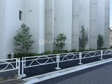 エスレジデンス駒場東大前 モダンな白い柱と植栽を備えた建物外観と駐車場の様子