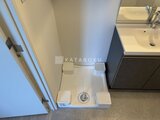 エスレジデンス駒場東大前 洗濯機置き場と黒い洗面化粧台が並ぶコンパクトな洗面スペース