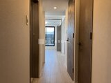 エスレジデンス亀戸バーム 明るい照明が導く落ち着いた色合いの廊下から各部屋へのアクセス
