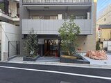 ブリリアイスト御茶ノ水 前面道路から見たモダンな建物外観と植栽のある玄関周り