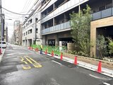 ブランシエスタ入谷グランデ 工事中の建設現場を囲む緑色の仮設フェンスと前面道路の様子
