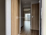 リテラス南千住サウス 木目調のドアと落ち着いた色合いの廊下から奥の洋室へ続く動線