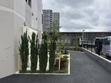 エスレジデンス千住大橋ブロード 緑化された駐車場から見た建物と周辺の様子